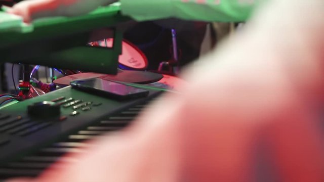 Man's hands playing piano on concert. Stylish hipster drummer hitting his drum kit while group performing music in nightclub.