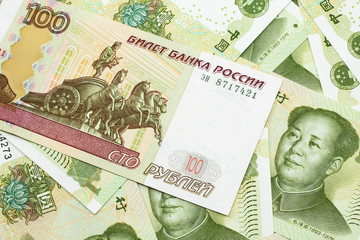 A close up image of a one hundred ruble bank note on a background of green, one Chinese yuan notes from the People's Republic of China.  Shot close up in macro