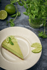 Slice of raw green cheesecake with lime and mint, decorated slice of lime. Healthy organic summer dessert pie.