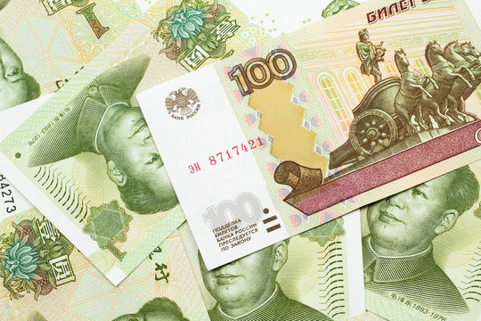 A close up image of a one hundred ruble bank note on a background of green, one Chinese yuan notes from the People's Republic of China.  Shot close up in macro