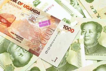 A close up image of a colorful Ugandan shilling bank note with Chinese one yuan bills in macro