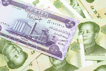 A purple Iraqi fifty dinar bank note close up in macro with an assortment of Chinese one yuan bank notes 