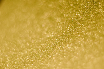 Abstract Christmast golden bokeh background with shining defocus sparkles. Blurred glitters shimmering dust macro close up, copy space for text logo