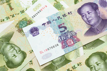 A close up image of a purple, five Chinese yuan bank note, close up on a background of green one yuan bank notes.  Shot in macro