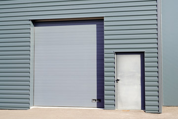 grey metal roll-down shutters on vertical profiled sheeting gray new industrial building