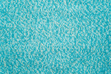 The texture of a blue turquoise knitted fabric. Sweater background