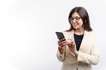 Fototapeta premium Cheerful female white collar in glasses using smartphone isolated white background copyspace