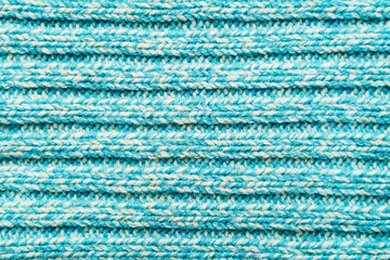 The texture of a blue turquoise knitted fabric. Sweater background