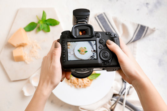 Female photographer taking picture of pasta on table