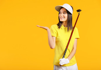 Beautiful female golfer showing something on color background