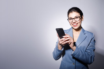 Portrait of young brunette business lady posing with smartphone isolated blue-gray background copyspace