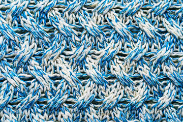 Blue and white texture of a knitted woolen fabric with a patterned weave. Sweater background
