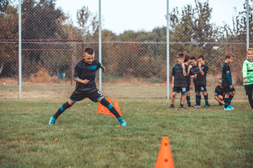 Kid in soccer jersey running between cones and ring ladder marker
