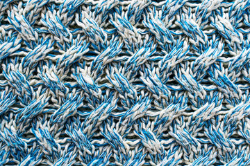 Blue and white texture of a knitted woolen fabric with a patterned weave. Sweater background