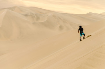 A guy is sand boarding at Huacachina Oasis, near Ica, Peru.