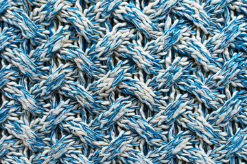 Blue and white texture of a knitted woolen fabric with a patterned weave. Sweater background