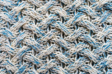 Blue and white texture of a knitted woolen fabric with a patterned weave. Sweater background