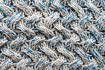 Blue and white texture of a knitted woolen fabric with a patterned weave. Sweater background