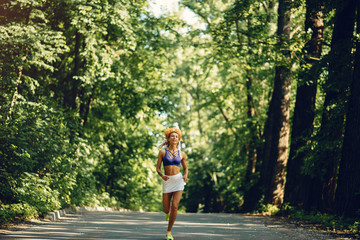 Girl training. Woman in a sports shorts. Redheads girl in a summer park