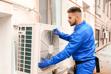 Male technician installing outdoor unit of air conditioner