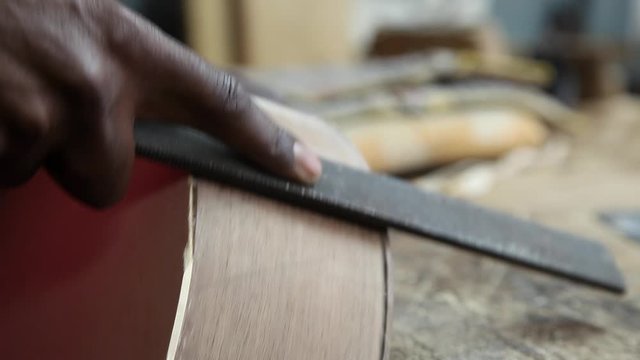 Craftman making guitar using chisel on wood