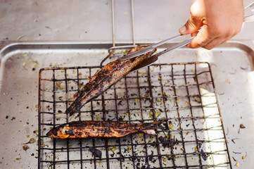 Master chief is grilling fish at open kitchen