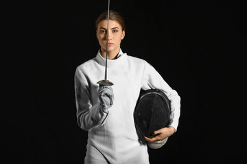 Young female fencer on dark background