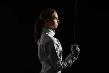 Young female fencer on dark background