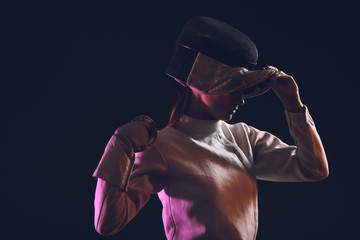 Young female fencer on dark background