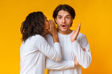 Black Girlfriend Whispering Secret To Her Shocked Boyfriend's Ear