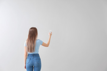 Young woman with air conditioner remote control on white background