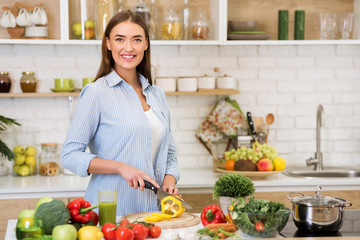 Cheerful woman preparing healthy veggies salad, free space