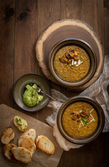 Vegan cream of mushroom soup on wooden table along with toasted bread and avocado