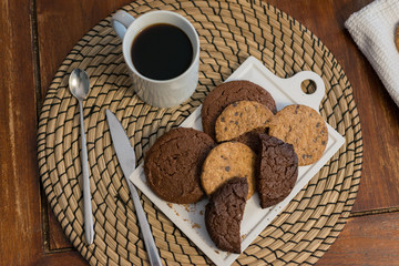 An overhead view of some sweet snacks, black coffee and cane sugar on a wooden table.