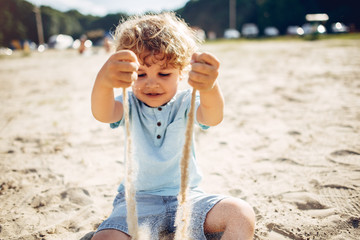 Beautiful little boy in a blue shirt. Childred playing in a summer beach. On a sand