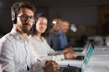 Confident bearded call center operator looking at camera. Handsome young man posing at workplace. Call center concept