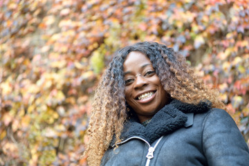 Portrait of a happy black afro girl with curly brown hair smiling and looking at the camera