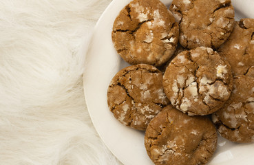 Pile of brown cookies on a white plate on white background