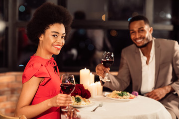 Couple Holding Glasses Smiling To Camera Sitting In Fancy Restaurant