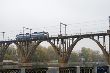 Locomotive moves along railroad arch bridge