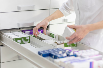 Pharmacien tenant une boîte à médicaments et un pack de capsules en pharmacie.