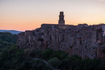 Fototapeta premium Panoramic view of small vilage in Italy with red brick houses and towers and nature at golden hour with beautiful sky clouds in Grosse province in Tuscany Italy during sunset and warm light