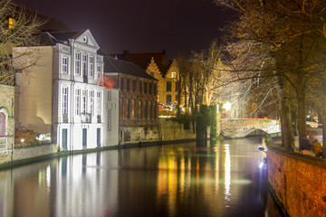 Picturesque night views to the channels and narrow streets of old Brugge in Belgium. Houses, boates, lights reflecting in the dark still water on the Christmas time.