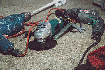 A set of power tools and tools on concrete ground. The concept of industrial work, renovation, physical work. On the ground lies a screwdriver, grinder, wrench.