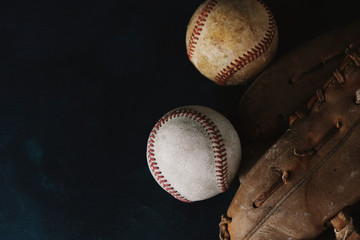Baseball sports balls on black background with copy space for sport, flat lay of vintage old ball with glove.