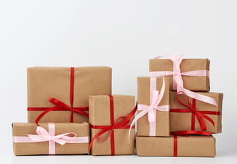stack of gifts in boxes wrapped in brown kraft paper and tied with silk ribbon