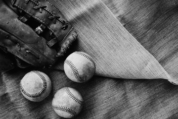 Old baseball balls on textile texture background in black and white, close up of ball game equipment for sport.