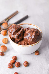 Tasty ice-cream in bowl and nuts on grey background