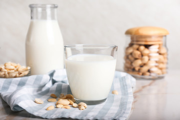 Glass of tasty peanut milk on white table