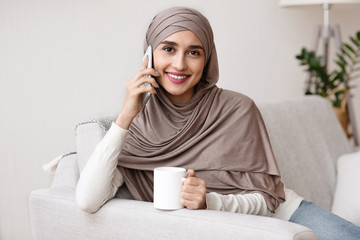 Happy Arabic Girl Calling To Friend And Drinking Coffee At Home